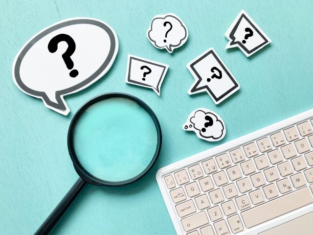 ？の吹き出しと虫眼鏡とキーボードの写真